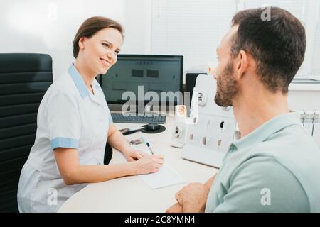 Konsultation, ein Audiologe kommuniziert mit einem erwachsenen Mann in einer Hörklinik. Arzt und Patient, Diagnose und Behandlung des Gehörs. Stockfoto