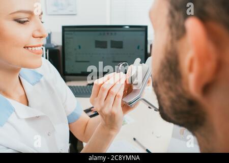 Der Arzt eines Audiologen informiert den Patienten über das Hörgerät. Auswahl an Hörlösungen, Hörbehandlung, in-Ear-Hörgeräten Stockfoto