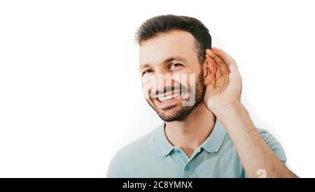 Überprüfen Sie Ihr Gehör. Positiver Mischling hält die Hand am Ohr, isoliert auf weißem Hintergrund. Gesundheit des Ohres, Behandlung und Diagnose des Hörers Stockfoto
