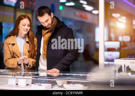 Junge kaukasische Paar in den Geschäften, beschlossen, Schmuck für Frauen in Mall.excited rothaarige Frau und jungen bärtigen Mann zusammen kaufen Stockfoto