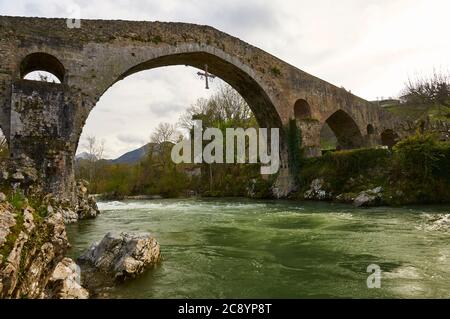 Die römische Brücke mit dem Kreuz Cruz de la Victoria, Symbol von Asturien, die über dem Fluss Sella (Cangas de Onís, Asturien, Spanien) hängt Stockfoto