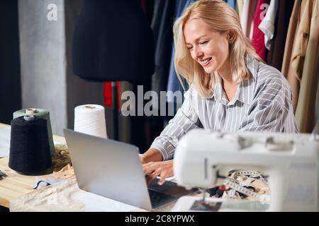 Lächelnd positive Schneider chatten mit ihrem Freund online, Schneider geben Empfehlungen, Beratung Kunden online. Close up Foto. Freelancer Stockfoto