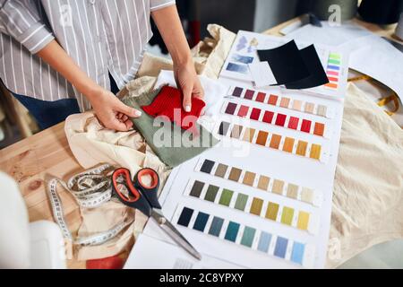 Schneiderei Vorbereitung Fäden zu nähen, stricken, Nahaufnahme abgeschnitten Foto. Frau hält gestrickten Stoff. Schneiderei Stockfoto