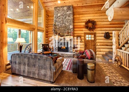 Ein luxuriöses Wohnzimmer, mit Kamin und komfortabler Einrichtung, in einer modernen Blockhütte in den Bergen. Stockfoto