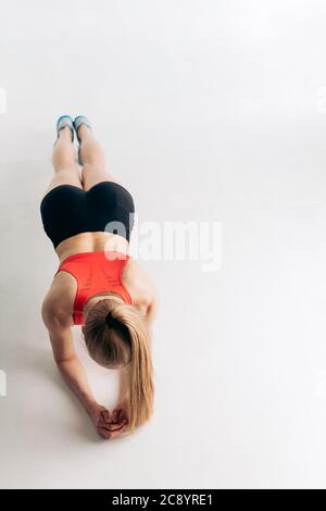 Fit actiav egirl in Sportbekleidung lehnt sich an ihre Ellbogen und macht Übungen. Draufsicht Foto. Copy space Stockfoto