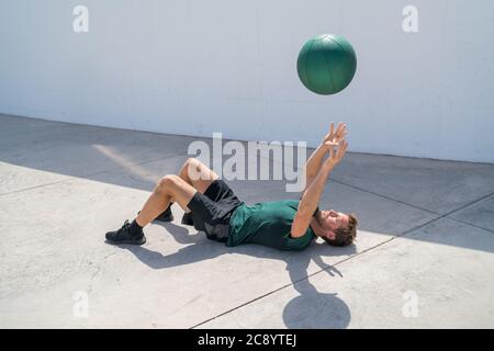 Ausbildung Mann werfen Medizinball in der Luft Stockfoto