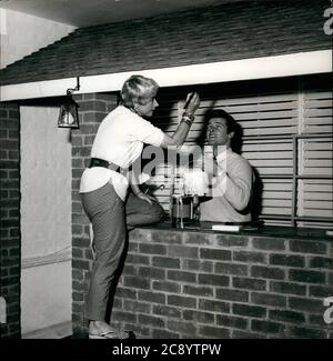 13. Aug. 1954 - London, England, Vereinigtes Königreich - ROGER MOORE und seine Sängerin Frau DOROTHY SQUIRES, machen eine Cocktail-Bar in ihrem Haus in Bexley Heath. In ihrer knappsten Freizeit, sie genießen es, malen es und immer es bereit für die nächste Saison Partys. (Bild: © Keystone Press Agency/Keystone USA via ZUMAPRESS.com) Stockfoto