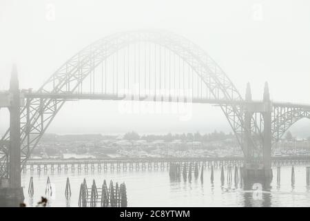 Ein nebliger Blick auf die Newport Brücke über den Yaquina Fluss in Oregon. Es gibt viele kommerzielle und private Fischerboote in der BA morred Stockfoto