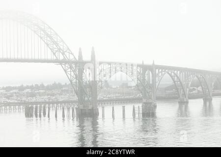 Ein nebliger Blick auf die Newport Brücke über den Yaquina Fluss in Oregon. Es gibt viele kommerzielle und private Fischerboote in der BA morred Stockfoto