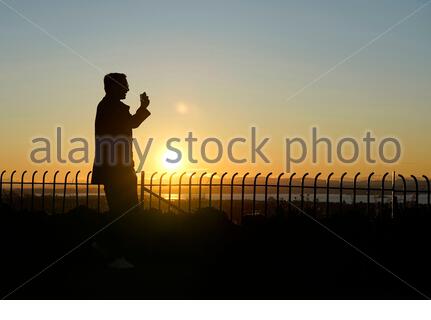 Die Menschen haben sich gegen die untergehende Sonne geschildet Stockfoto