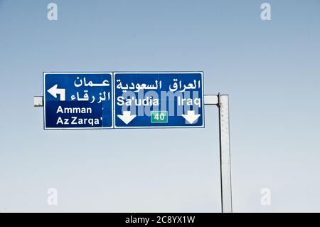 Ein Autobahnschild am Stadtrand von Amman, das die Richtung der Hauptstadt Zarqa, Saudi-Arabien und Irak im Haschemitischen Königreich Jordanien angibt. Stockfoto