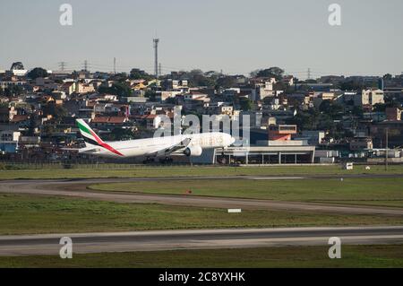 Emirates Boeing 777-31HER (Großraumflugzeug - Reg. A6-ECU) kurz vor der Berührung der Landebahn 27L von Sao Paulo / Guarulhos Intl. Flughafen. Stockfoto