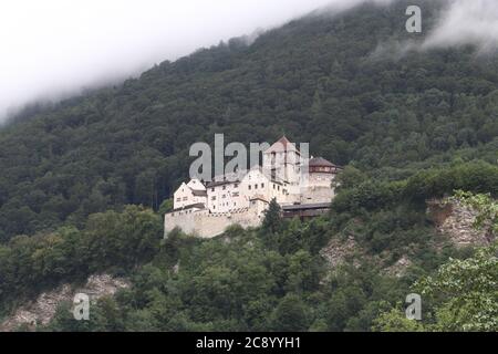 Vaduz / Liechtenstein - August 10 2019: Schloss Vaduz hoch im Berg auf der Spitze der Stadt Vaduz, Bäume in Wolken bedeckt Stockfoto