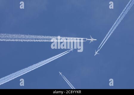 Passagierflugzeuge, die mit Chemtrails in einem blauen Himmel kreuzen Stockfoto