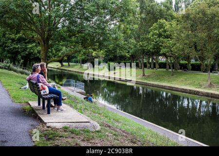 Hythe Military Canal. Ein Mann und eine Frau sitzen auf einer Bank und entspannen sich am Wasser. Stockfoto