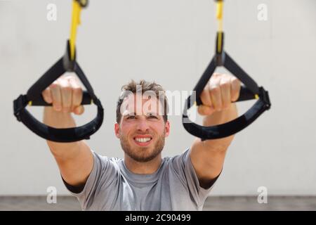 Suspension Straps Übungen Mann Training Arme Workout im Outdoor-Fitness-Studio. Athlet hält hängende trx Griffe tun schräg Pull-ups für Rückenmuskulatur Stockfoto