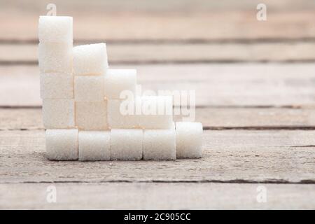 Der raffinierte Zucker, der von der Pyramide auf den hölzernen Tisch aus den alten Brettern gestellt wird. Stockfoto