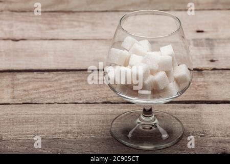 Das Cognacglas gefüllt mit dem raffinierten Zucker in Würfel auf einem Holztisch aus alten Brettern, niemand. Stockfoto