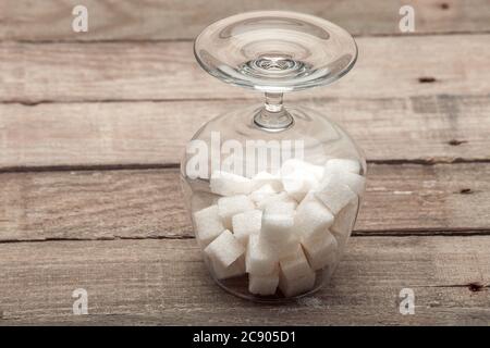 Cognac Glas Kopf über Fersen mit dem raffinierten Zucker in Würfel auf einem Holztisch aus alten Brettern gefüllt, niemand. Stockfoto