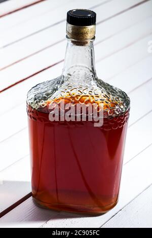 Cognac-Flasche auf einem weißen Tisch aus Brettern, alkoholisches Getränk auf einem hölzernen Hintergrund. Stockfoto