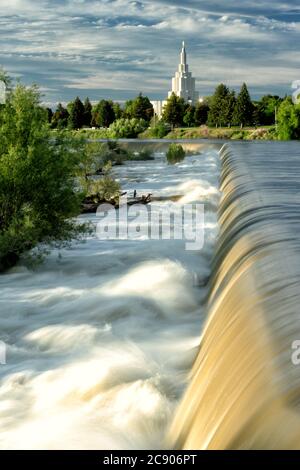 Eine Hochwasserfrühlingsansicht des Wasserfalls, nach dem die Stadt Idaho Falls, ID USA benannt ist. Der Idaho Falls LDS Tempel im Art Deco Stil ist in Stockfoto