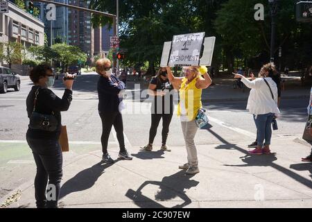 Eine Mutter Protesterin in gelben Posen für einen Videofilmer vor dem Bundesgericht Gebäude in der Innenstadt von Portland, Oregon, am Samstag, 25. Juli 2020. Stockfoto