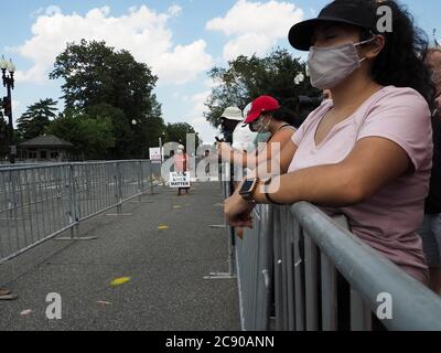 Washington, District of Columbia, USA. Juli 2020. Menschenmassen versammeln sich, um den Sarg zu beobachten, der den verstorbenen Rep. John Lewis trägt, der die Capitol Steps zur Capitol Rotunda hinaufgetragen wird. Eine Frau trägt an Black Lives Matter Zeichen steht in der Nähe eines gelben Punkt, der die sichere soziale Distanz für Menschen Schlange, um dem Kongressabgeordneten seine letzten Respekt zu bieten markiert. Kredit: Sue Dorfman/ZUMA Wire/Alamy Live Nachrichten Stockfoto