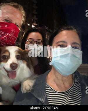 Kopf und Schultern Porträt der Familie mit Hund Tragen Schutzmasken bei Nacht, New York City, New York, USA Stockfoto