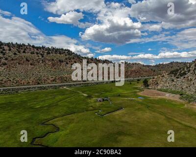 Luftaufnahme von grünem Land und kleinen Kurve Fluss mit Berg im Hintergrund in Aspen Springs, Mono County California, USA Stockfoto