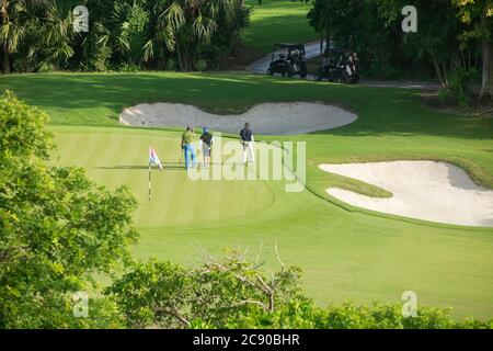 Eine Gruppe von Freunden auf dem Golfplatz, die eine gute Zeit haben. Sie gehen Seite an Seite in einem spielerischen Gespräch mit ihren Golfwagen - Playa del Carmen, Mexiko Stockfoto