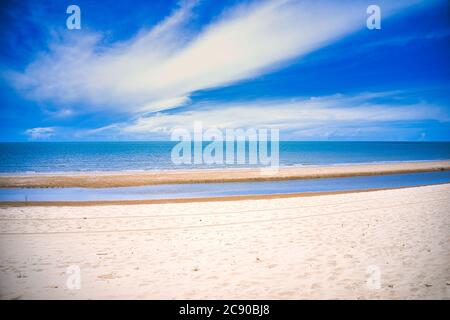 Dieses einzigartige Foto zeigt den Strand von Pak Nam Pran in Thailand bei Ebbe und mit einem hellen blauen, aber leicht bewölkten Himmel im Sommer. Stockfoto