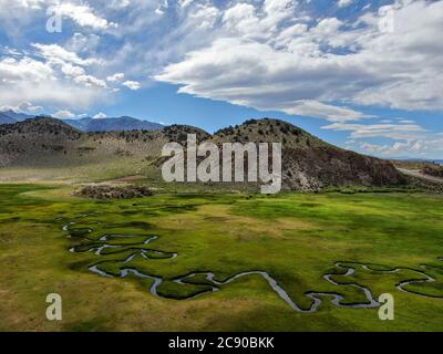 Luftaufnahme von grünem Land und kleinen Kurve Fluss mit Berg im Hintergrund in Aspen Springs, Mono County California, USA Stockfoto