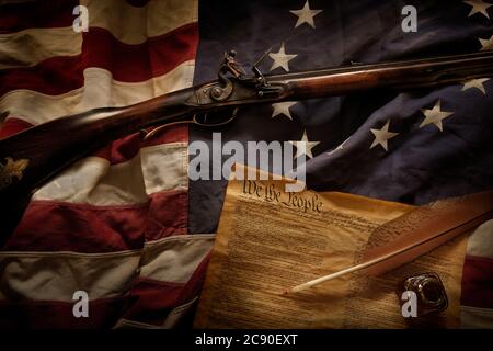 Gewehr und US-Verfassung liegen auf amerikanischer Flagge Stockfoto