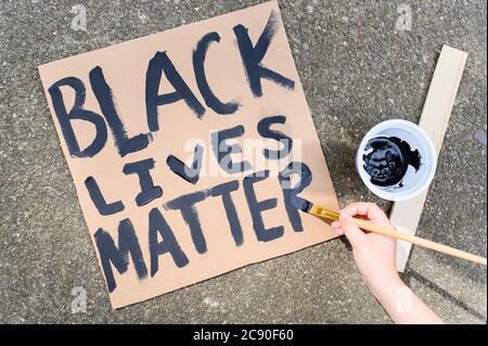 Frau Handgemälde Black Lives Matter Zeichen auf Karton Stockfoto