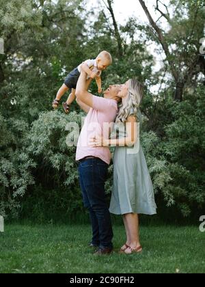 Glückliche Eltern spielen mit Baby Sohn im Garten Stockfoto