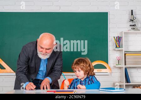 Schüler und Lehrer im Klassenzimmer. Oberlehrer mit Schüler im Klassenzimmer an der Grundschule. Stockfoto