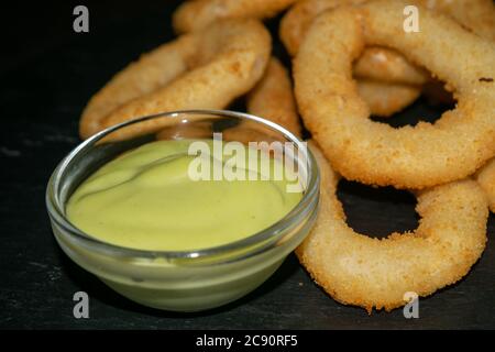 Zwiebelringe und ein Glas-Topf mit Sauce. Nahaufnahme Stockfoto