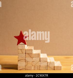 Roter Stern auf Holzblocktreppe mit braunem Hintergrund. Business Development, Growth, Success Concept. Mit Kopierplatz Stockfoto