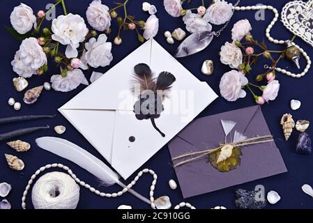 Zwei verzierte Umschläge mit Rosen und magischen Objekten auf dem Tisch. Mystischer und romantischer Hintergrund mit Kopierraum und leerem, vintage romantischem Konzept für m Stockfoto