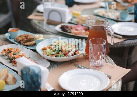 Leckerer Salat mit rotem Fisch auf der Sommerterrasse im Restaurant. Food-Konzept. Verschiedene Speisen und Getränke auf dem Tisch Stockfoto