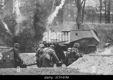 Re-enactors als deutsche Soldaten im Zweiten Weltkrieg gekleidet kämpfen Schießen mit EINER Kanone auf dem russischen sowjetischen Panzerwagen während der historischen Stockfoto