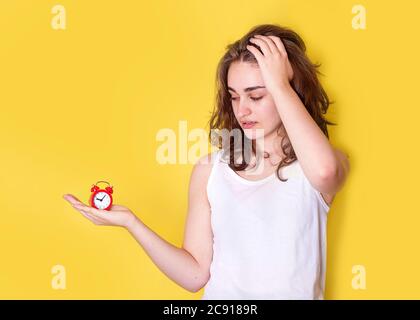 Junge Frau, die auf eine Uhr und den Kopf schaut. Sie ist zu spät. Stockfoto