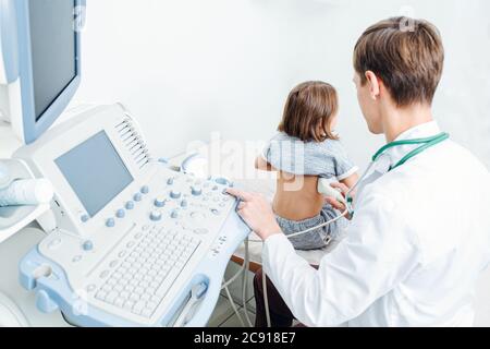 Junger Arzt, der eine Ultraschalluntersuchung der Nieren an einem zehnjährigen Mädchen durchführt Stockfoto