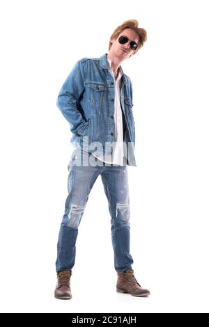 Neugierige junge stilvolle Mann in Jeans mit Händen in Jackentaschen Blick auf die Kamera mit verdächtig. Ganzkörperlänge isoliert auf weißem Hintergrund. Stockfoto