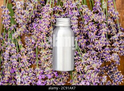 Lavendel ätherisches Öl Metall silberne Flasche auf frischen Lavendelblüten. Flach Lay Apotheker Kräuter für Aromatherapie-Behandlung. Lavendel Hautpflege Kosmetik Stockfoto