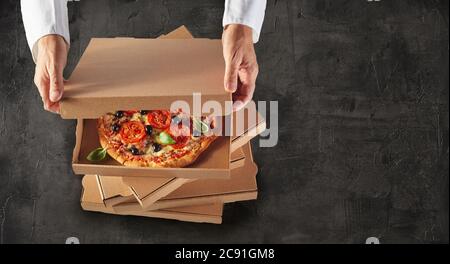 Koch Verpackung frische Ofenpizzas in Boxen für eine Take-away-Bestellung angesehen hohen Winkel in einem Panorama-Banner mit Copyspace Stockfoto