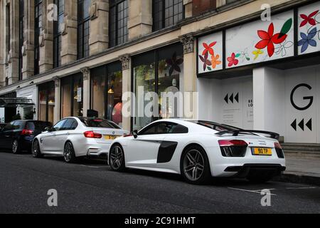 Weißer Audi R8 moderner Supersportwagen hinter weißer BMW M3 F80 Performance Limousine in Central London. Stockfoto