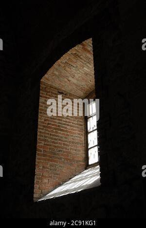 Vertikale Aufnahme von Licht, das durch ein Fenster in einem kommt Steinwand Loch Stockfoto