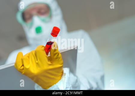 Virologe mit Blutprobe Laborschlauch, der Hinweise in Virusquarantäne schreibt Stockfoto