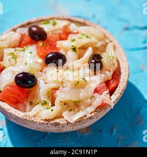 Nahaufnahme eines Tellers mit Esqueixada de bacalla, einem kalten Gericht mit Kabeljau, Tomaten, Zwiebeln und schwarzen Oliven, und mit Olivenöl, typisch für C gekleidet Stockfoto